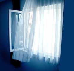an open window with curtains fluttering