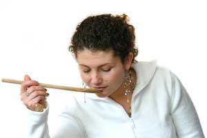 woman tasting food with wooden spoon